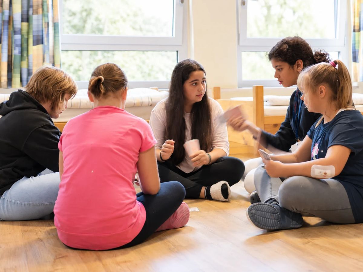 Die Kinder sitzen in einem Kreis und sprechen miteinander 
