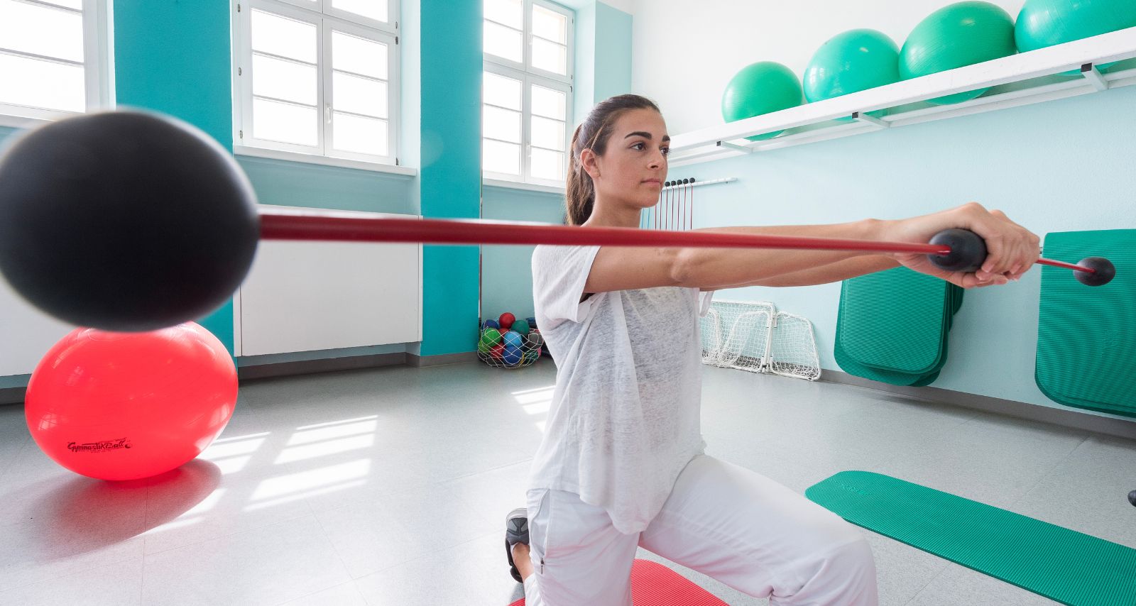 Eine Frau die in einem Raum mit einem Stab eine Übung macht 