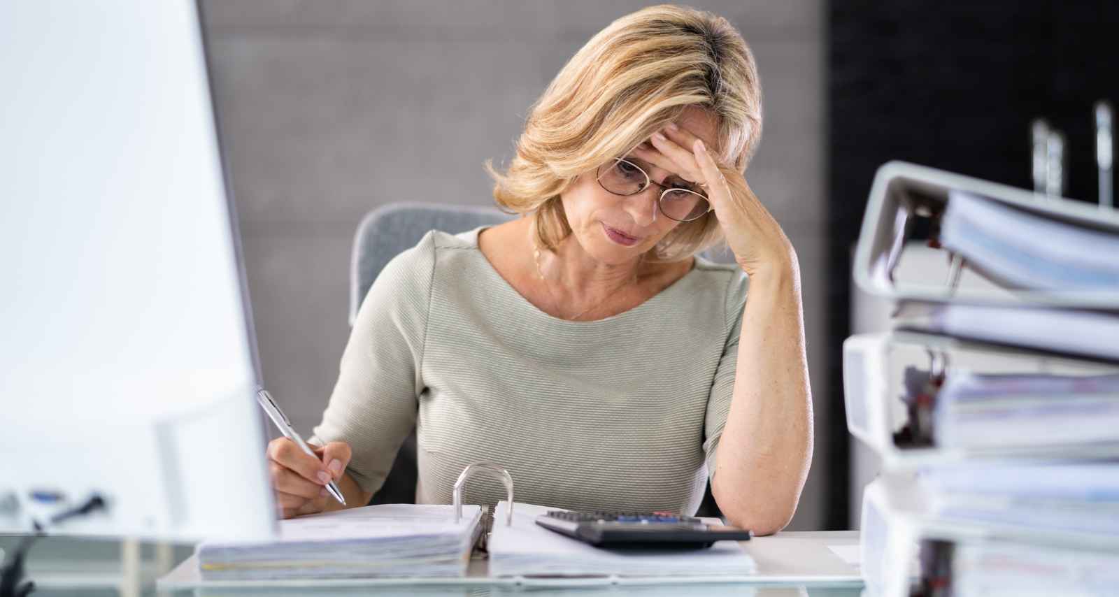 Eine Frau sitzt am Schreibtisch mit vielen Heftern 