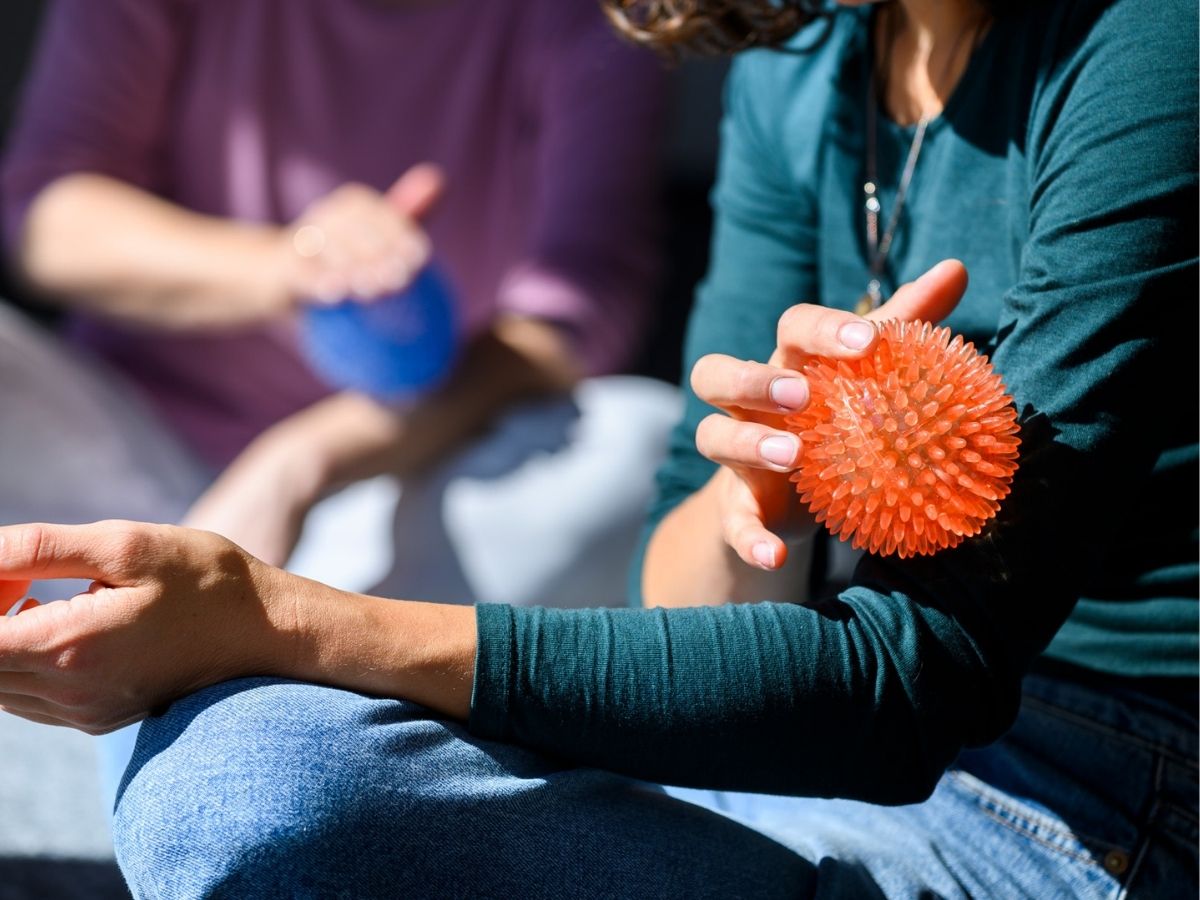 Personen gehen mit einem Ball über ihren Körper im Rahmen eines Entspannungsverfahren