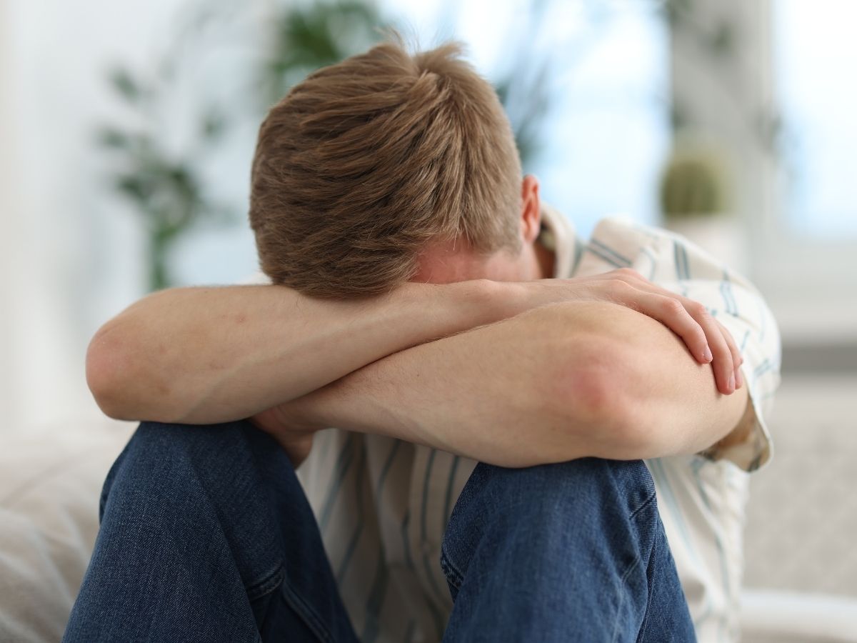 Ein Junge der seine Arme verschränkt und und an seinen Kopf hält 