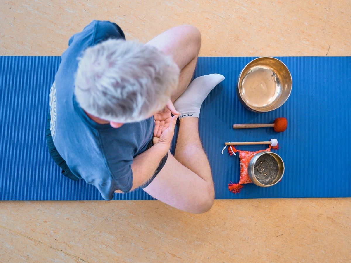 Eine Person sitzt auf einer Matte und Meditiert 