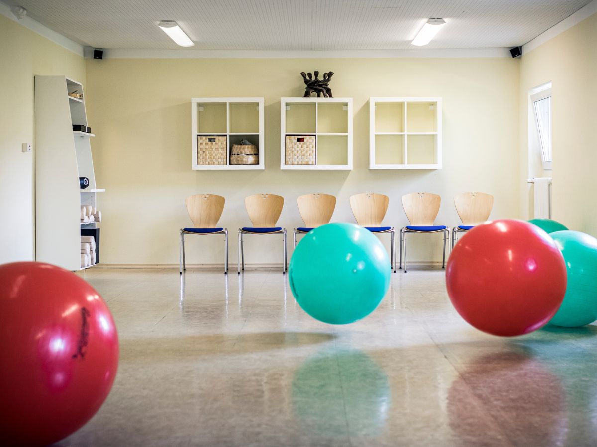 Im Raum sind zwei rote Gymnastikbälle und zwei grüne Gymnastikbälle