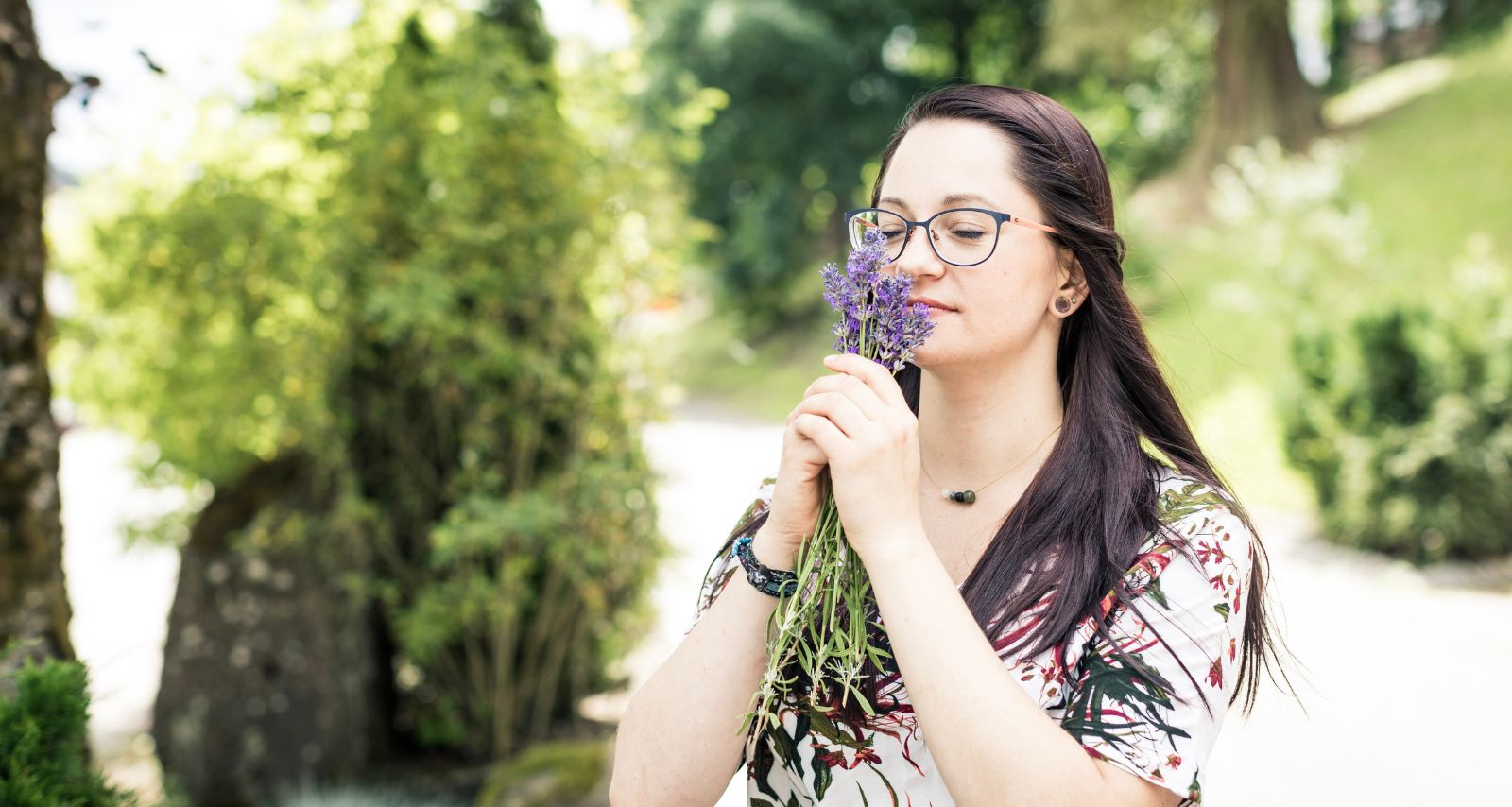 Eine Frauen die draußen an einer Blume riecht