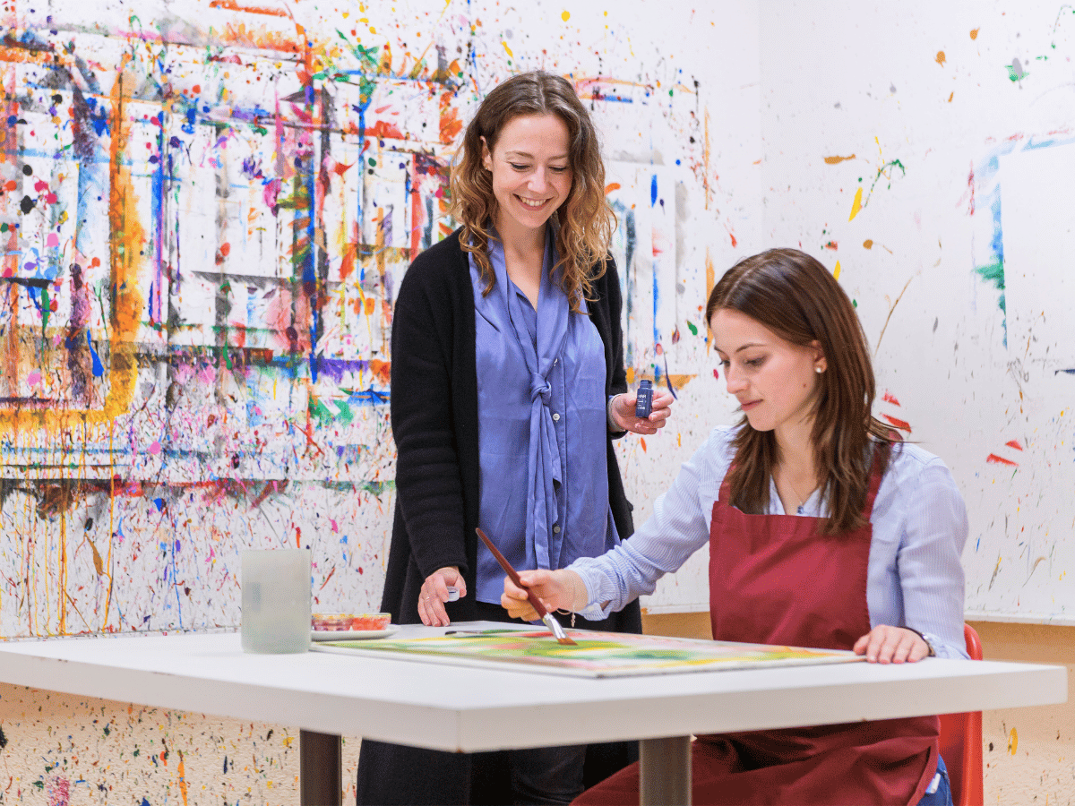 Die Frau zeichnet und die Lehrerin schaut zu 