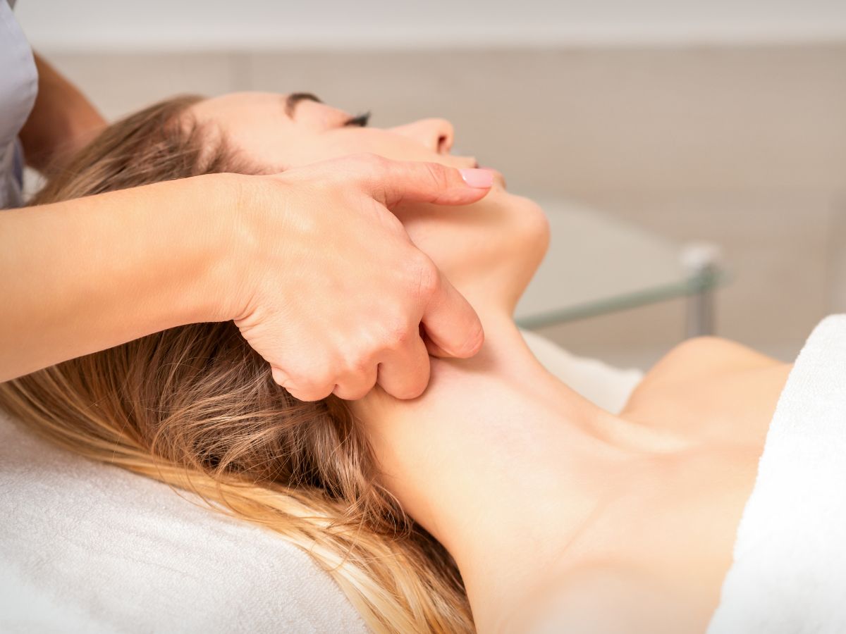 Eine Frau die sich am Hals massieren lässt 