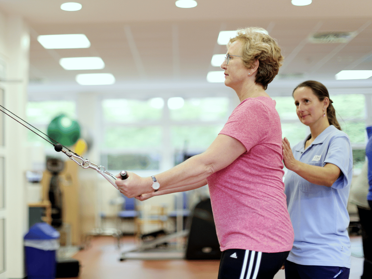 Die Frau führt eine Übung durch und bekommt dabei Hilfe 