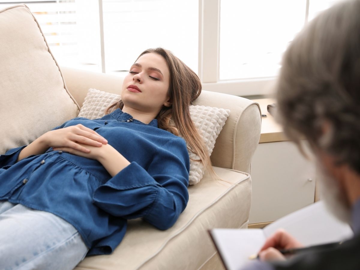 Die Frau hat einen blauen Pulli an und redet mit der Person vor ihr 