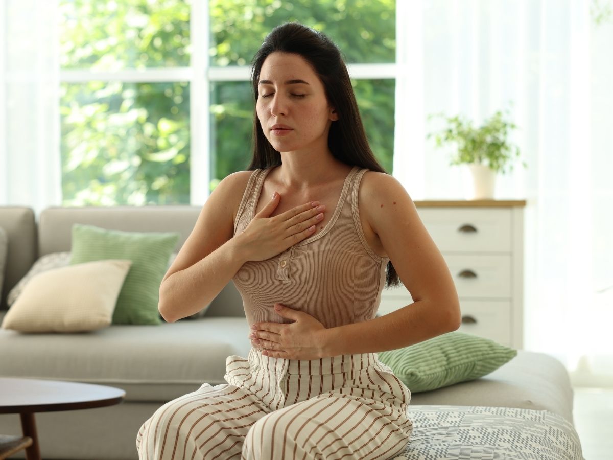 Die Frau fasst mit ihren Händen ihren Bauch und ihr Dekolleté an 