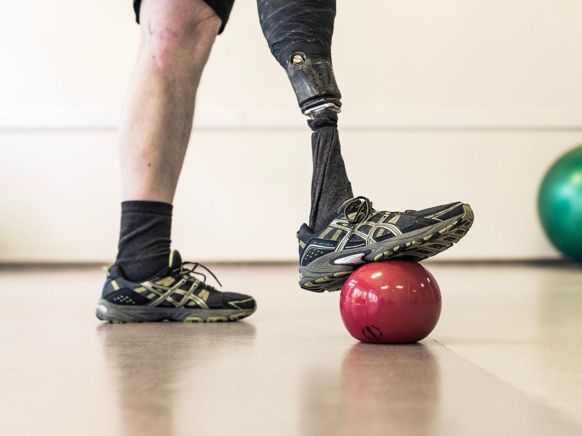 Eine Person tritt mit seinem Bein auf einen Ball im Rahmen einer Physikalischen Therapie