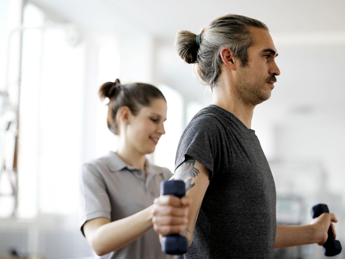 Ein Mann der eine Übung macht mithilfe einer anderen Person 