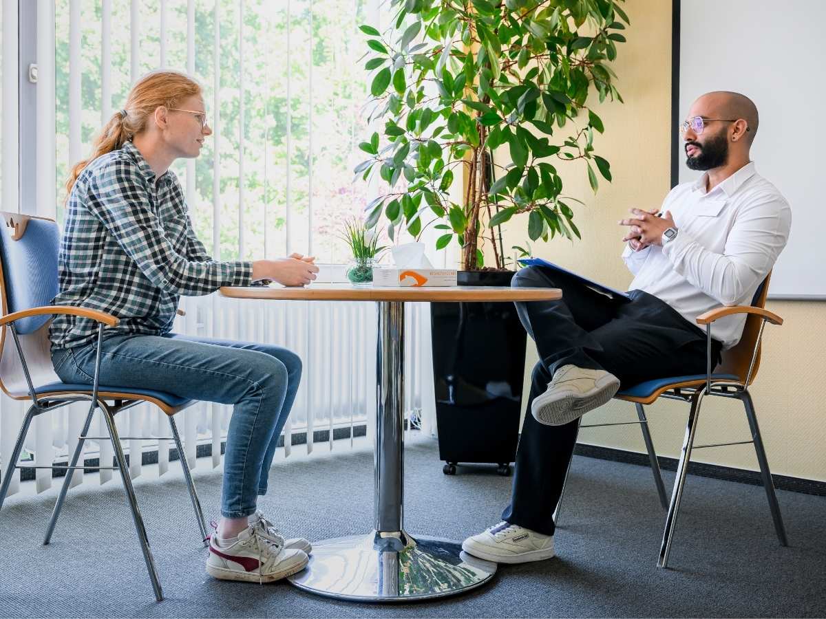 Eine Frau und ein Mann sitzen im Rahmen eines therapeutischen Gesprächs an einem Tisch.