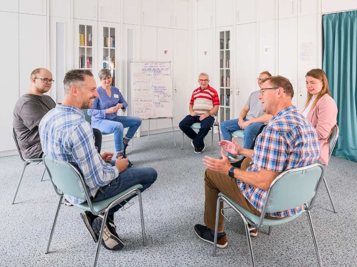 Eine Gruppe die sich unterhält und im Kreis sitzen 