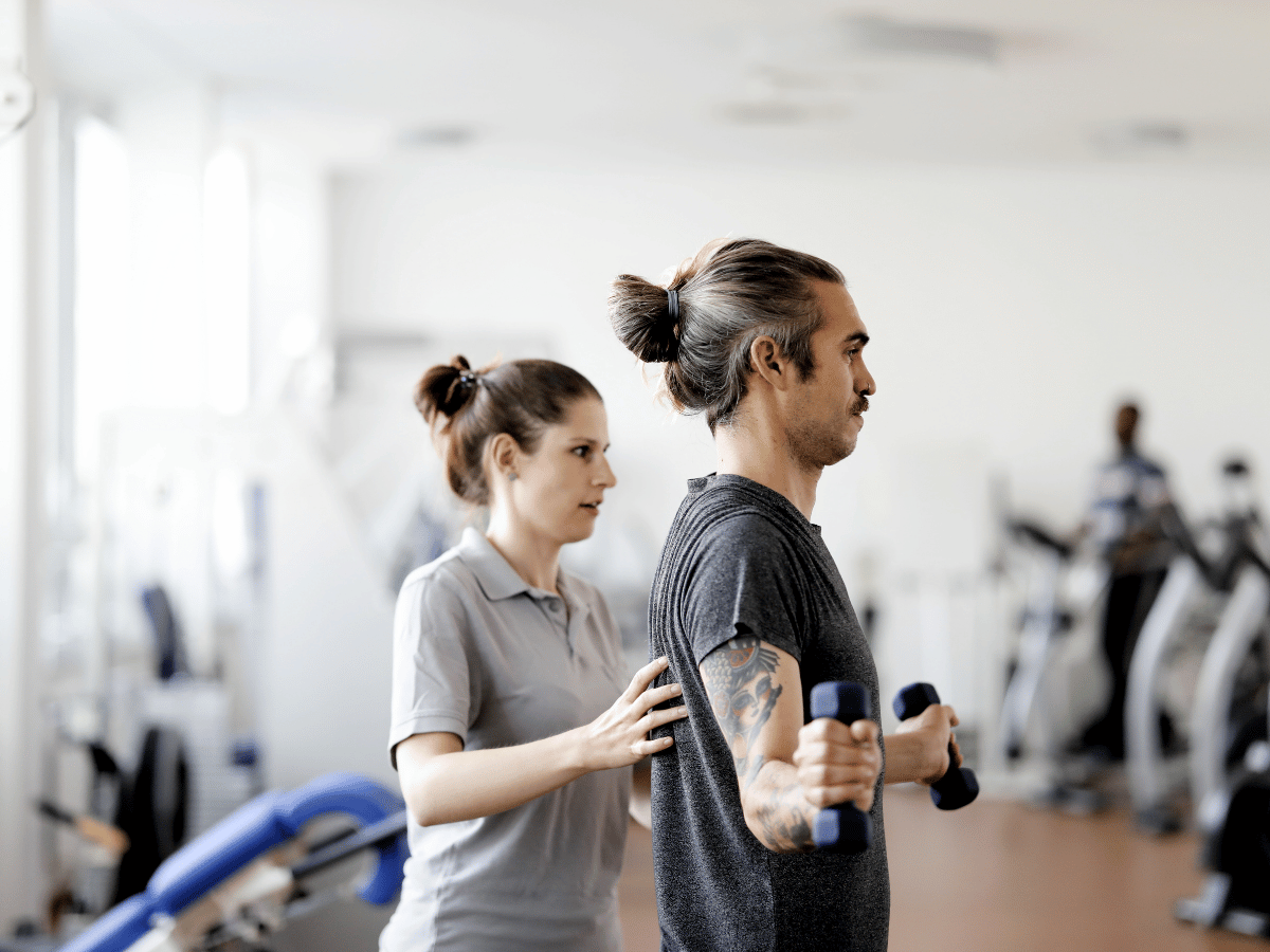 Ein Mann der eine Übung macht mithilfe einer anderen Person 