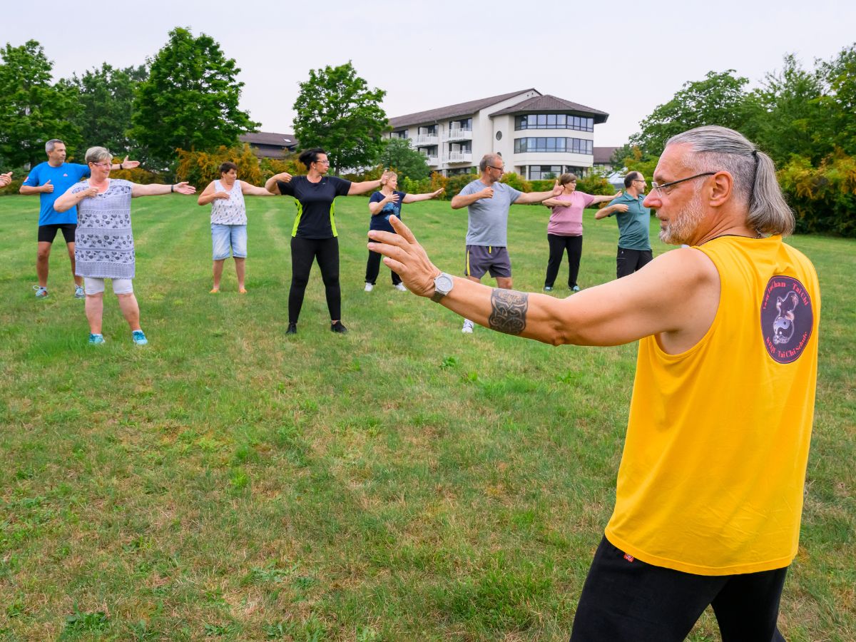 Der Mann macht die Übungen vor und die Gruppe macht diese nach 