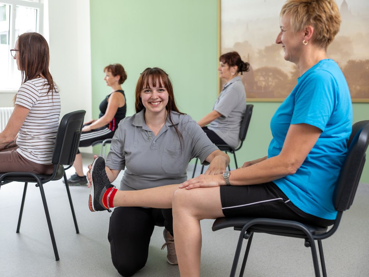 Eine Pflegerin die dem Mann hilft das rechte Beine hoch zubekommen 