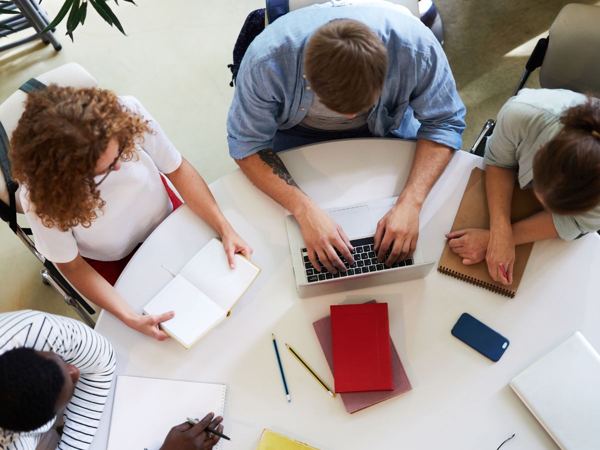 Vier Personen sitzen in einem Stuhlkreis und schreiben