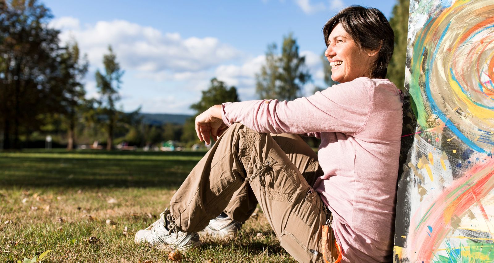 Eine Frau sitzt und lehnt sich an einen Stein