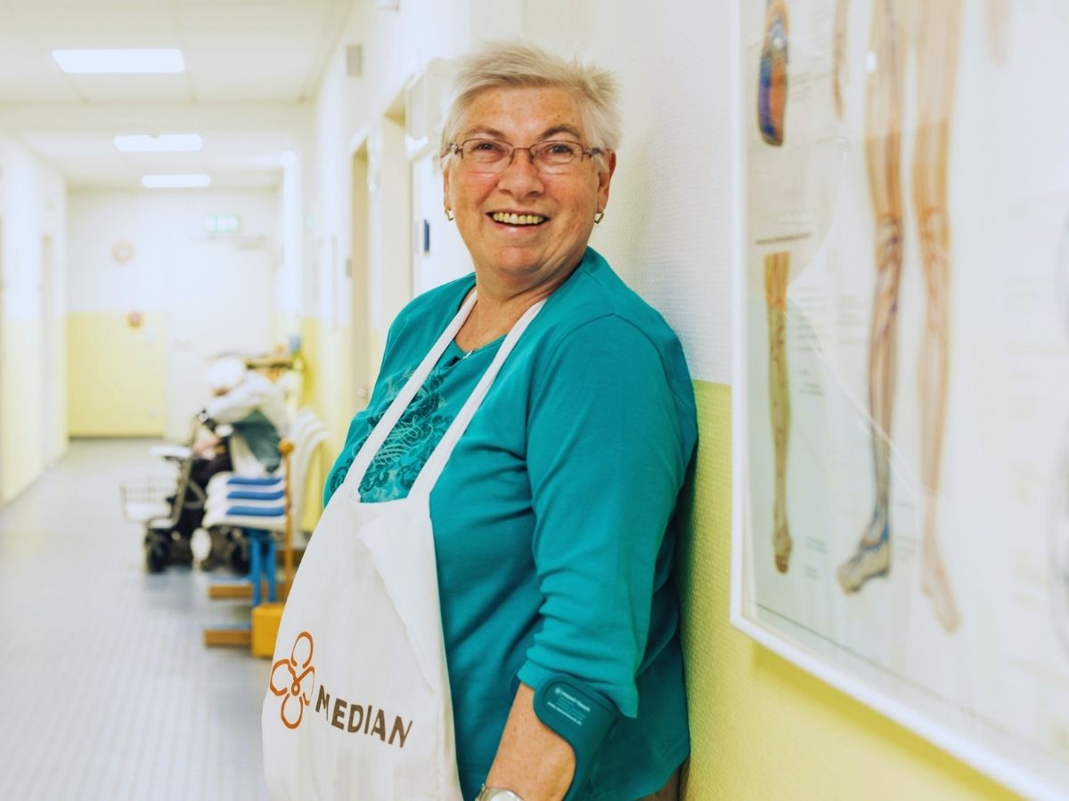 Eine Frau mit türkisen Shirt und MEDIAN Schürze, lächelt 