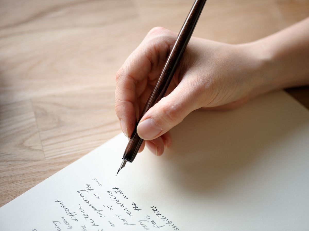 Eine Person schreibt auf ein Blatt Papier 