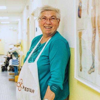 Eine Frau mit türkisen Shirt und MEDIAN Schürze, lächelt 
