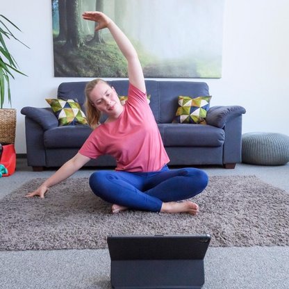 Eine Frau die die Übungen nach macht die auf ihrem Laptop gezeigt wird 