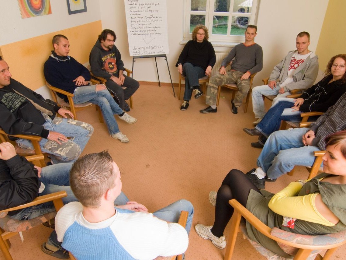 Personen sitzen im Stuhlkreis