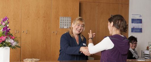 Rezeptionistin heißt eine Patientin willkommen in der MEDIAN Heinrich-Mann-Klinik Bad Liebenstein