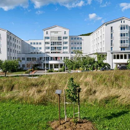 Klinikgebäude mit Eingangseite im Vordergrund eine Wiese