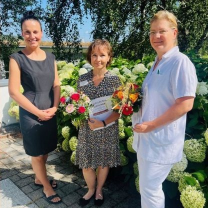 Drei Personen die nebeneinander stehen und Blumen halten 