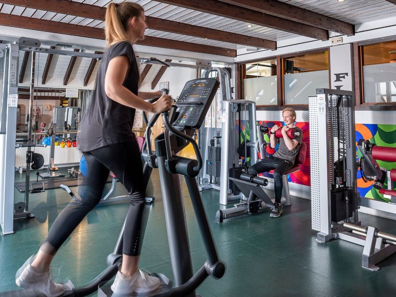 Frau trainiert ihre Kondition auf einem Crosstrainer im Fitnessraum
