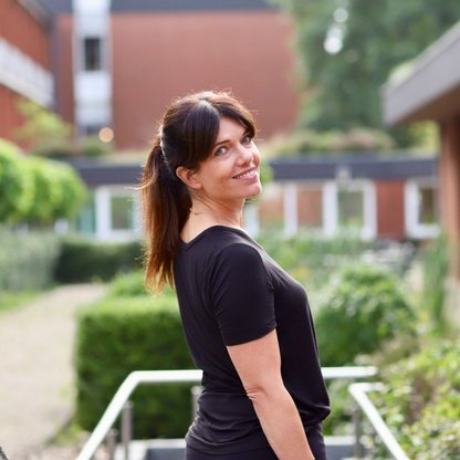 Eine Frau mit schwarzem Oberteil lächelt 