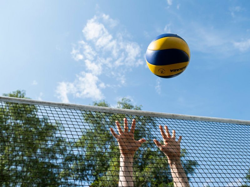 Hände spielen den Volleyball über das Netz