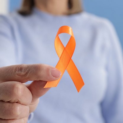Frau hält orangefarbene Bewusstseinsschleife für Multiple Sklerose (MS). Die Schleife steht weltweit für Aufklärung, Solidarität und Unterstützung von Menschen mit MS.