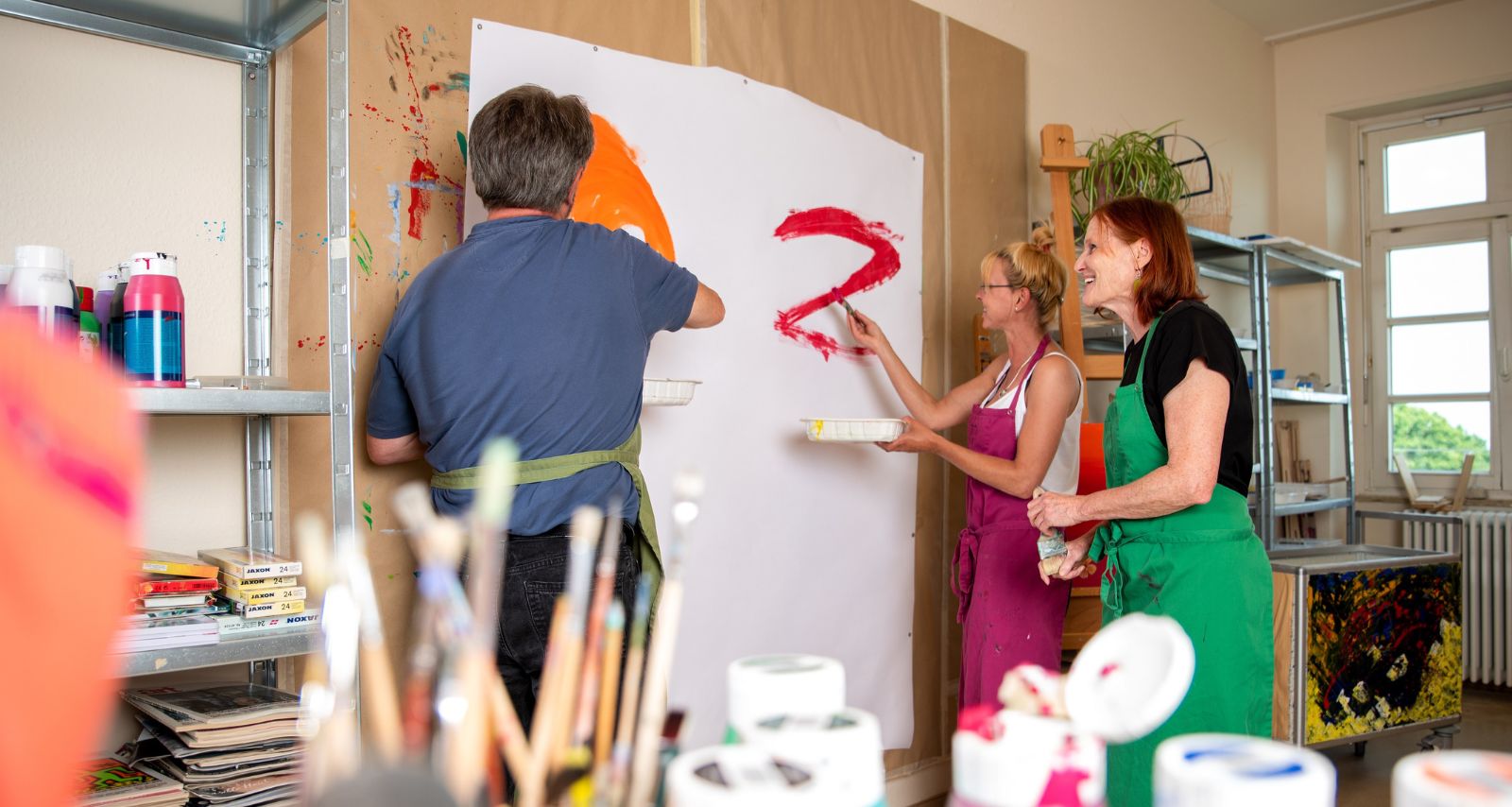 Personen die gemeinsam eine Leinwand bemalen 