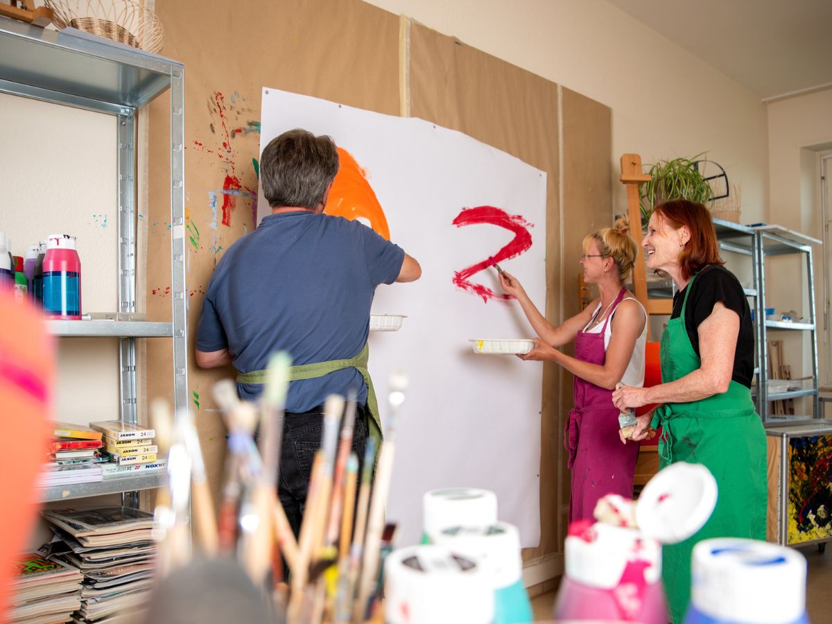 Personen die gemeinsam eine Leinwand bemalen 