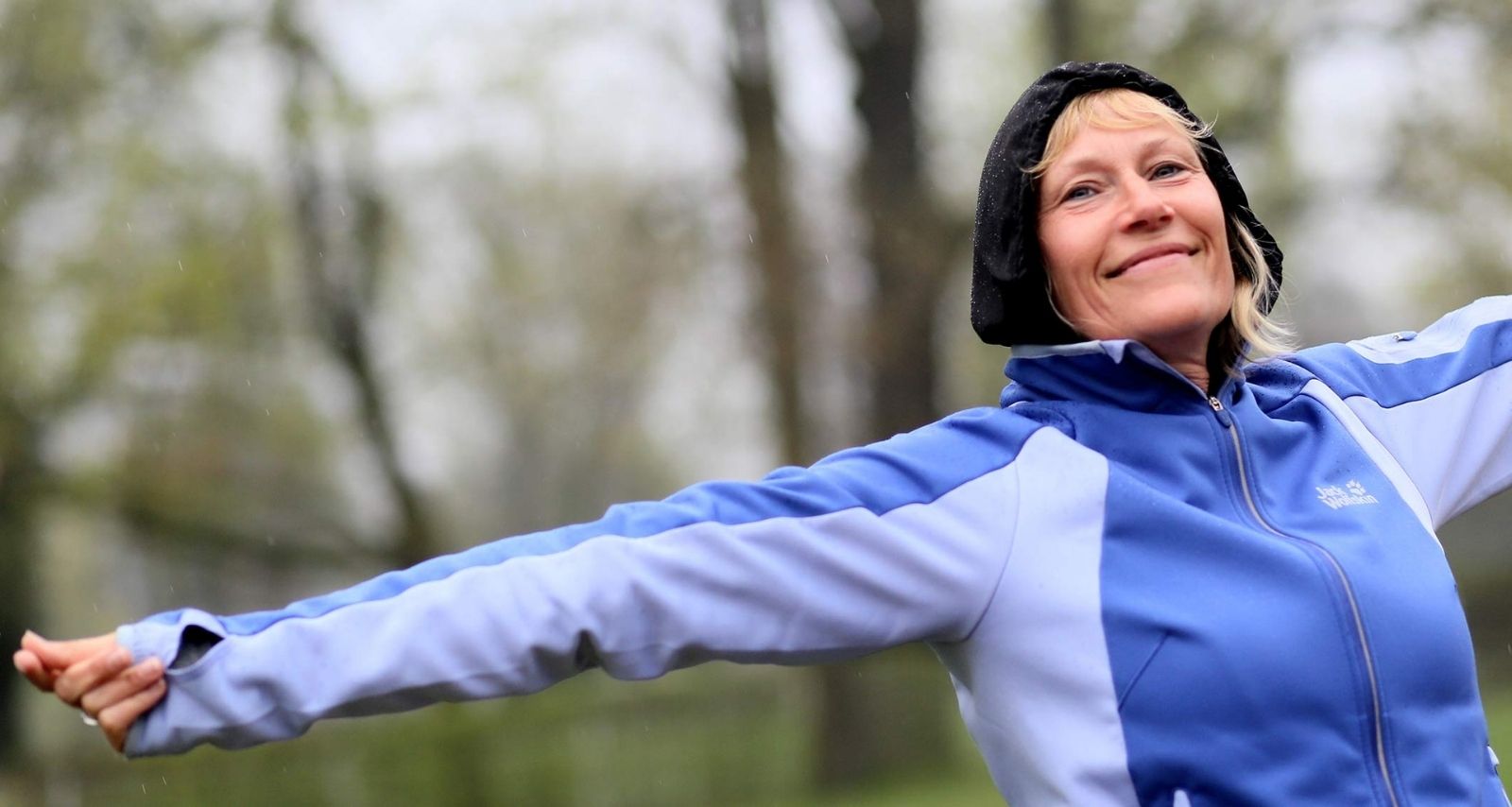 Patientin in blauer Trainingsjacke streckt sich und lächelt