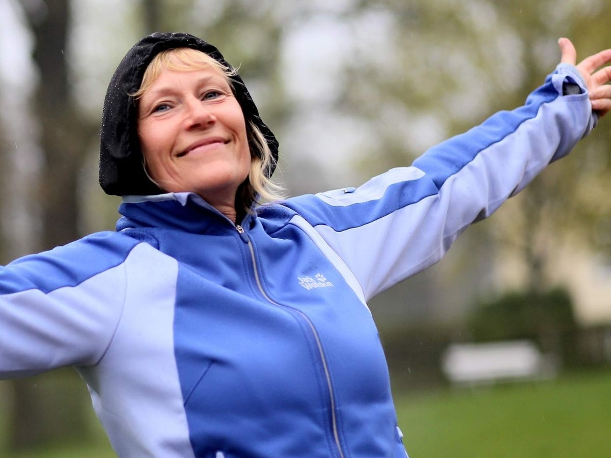 Patientin in blauer Trainingsjacke streckt sich und lächelt