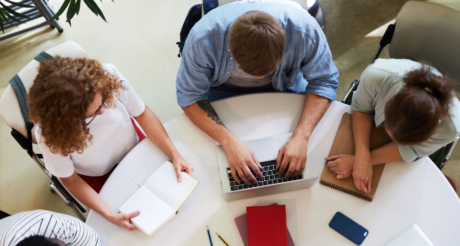 Personen die zusammen an einem Tisch sitzen und schreiben 
