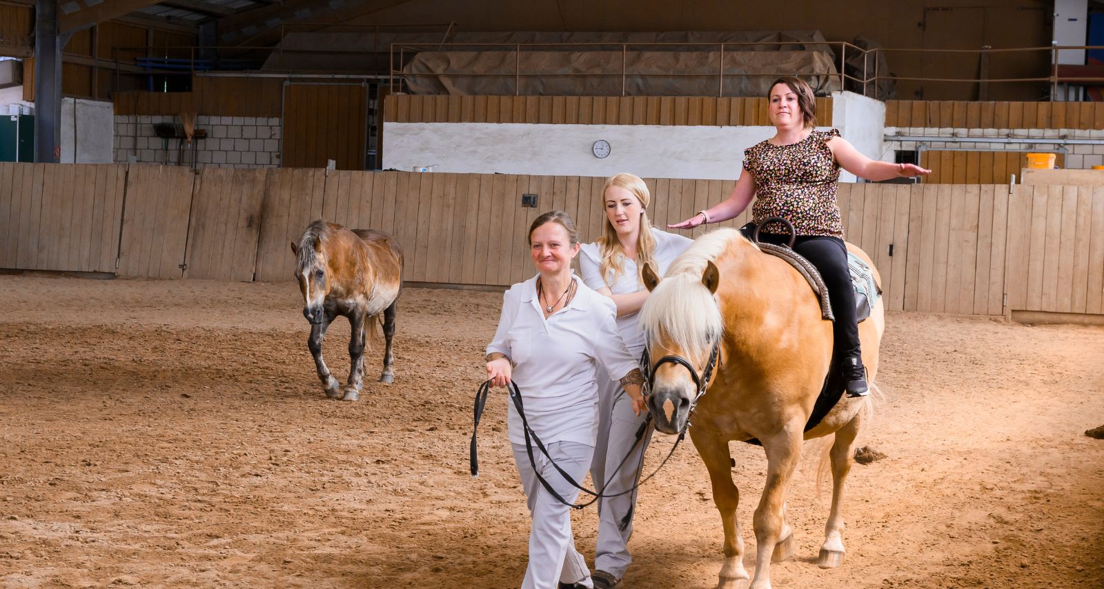 Patientin auf dem Pferd in Bergleitung von Therapeuten