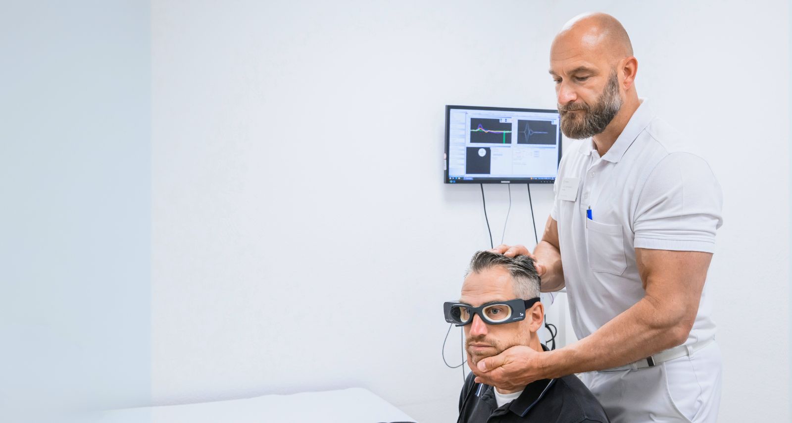 Arzt hält den Kopf des Patienten in den Händen und neigt diesen zur Seite