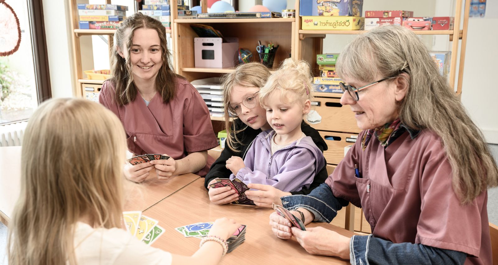 Eine gruppe von Mädchen und Therapeutinnen spielen Karten