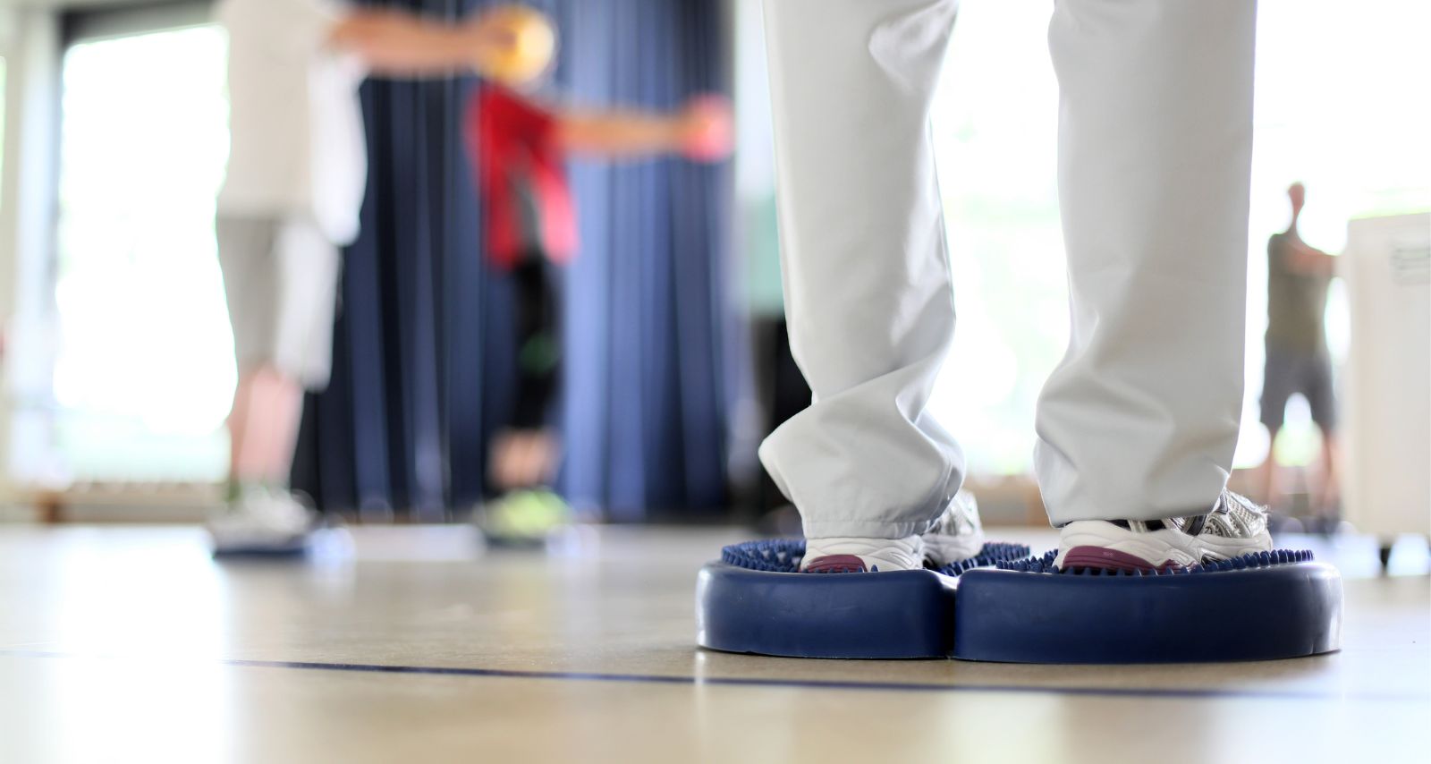 Patientengruppe bei Gleichgewichtsübungen im Sportraum