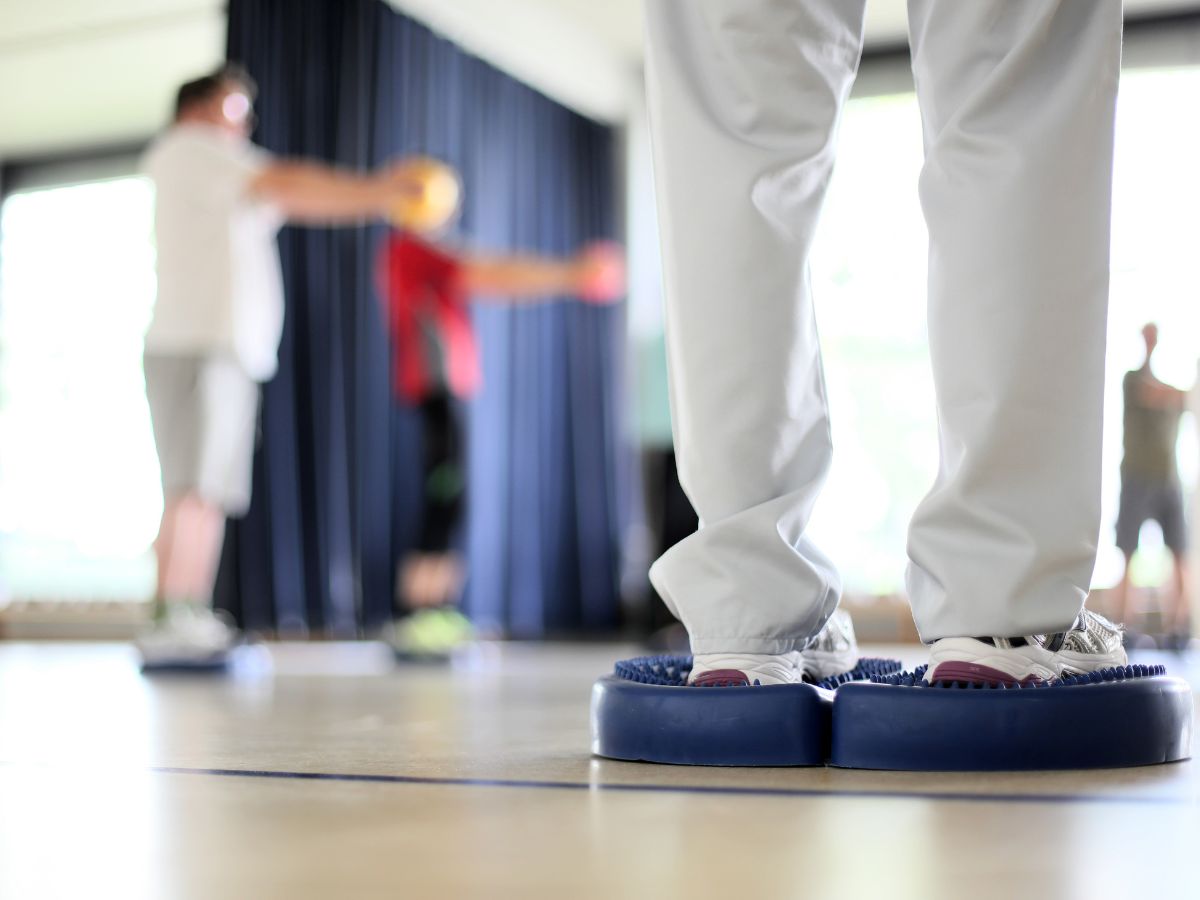 Patientengruppe bei Gleichgewichtsübungen im Sportraum