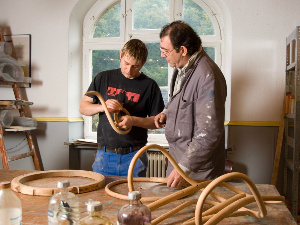 Zwei Personen die gemeinsam mit Holz arbeiten 