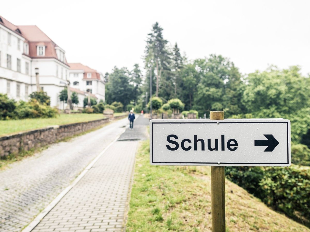 Ein Schild wo Schule drauf steht mit einem Pfeil nach rechts 