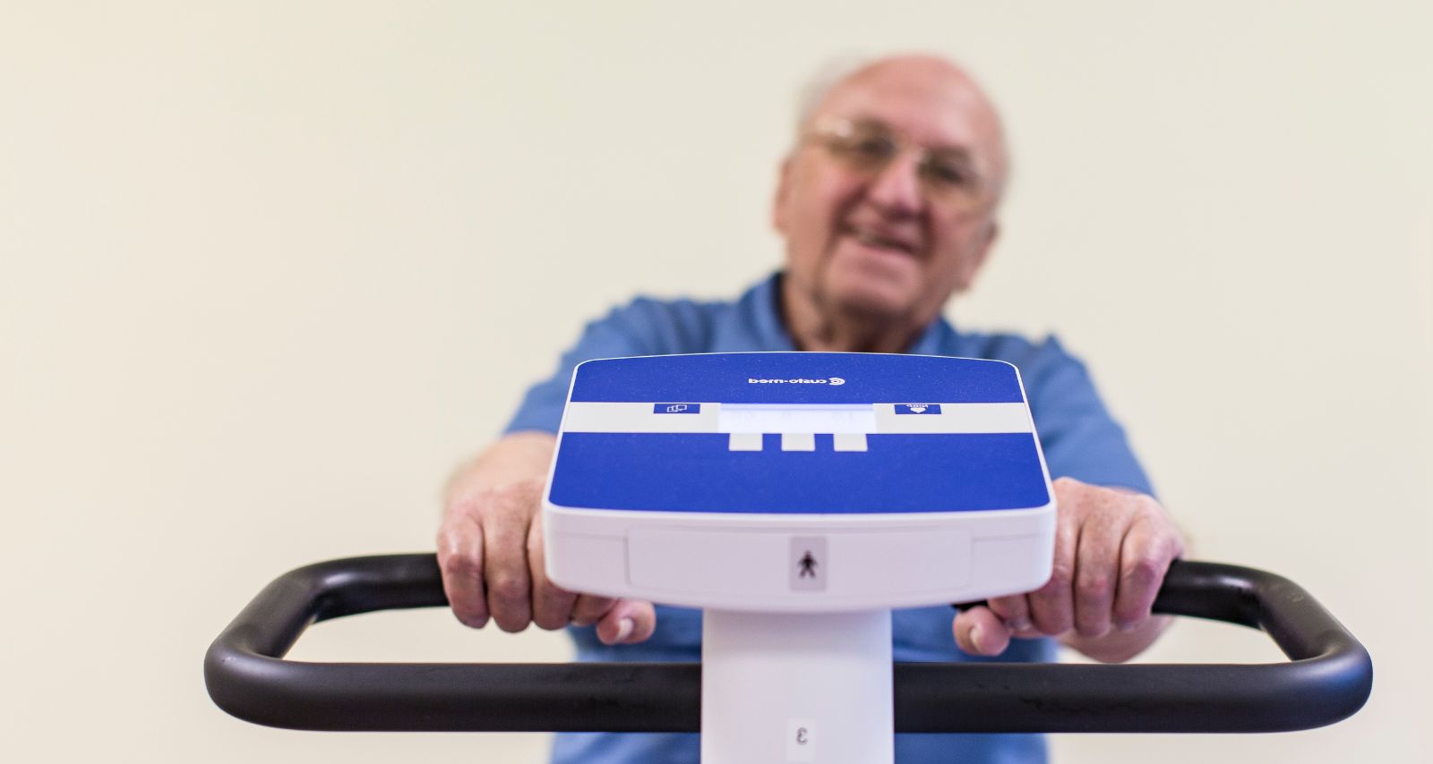 Mann mit Brille sitzt auf dem Ergometer.