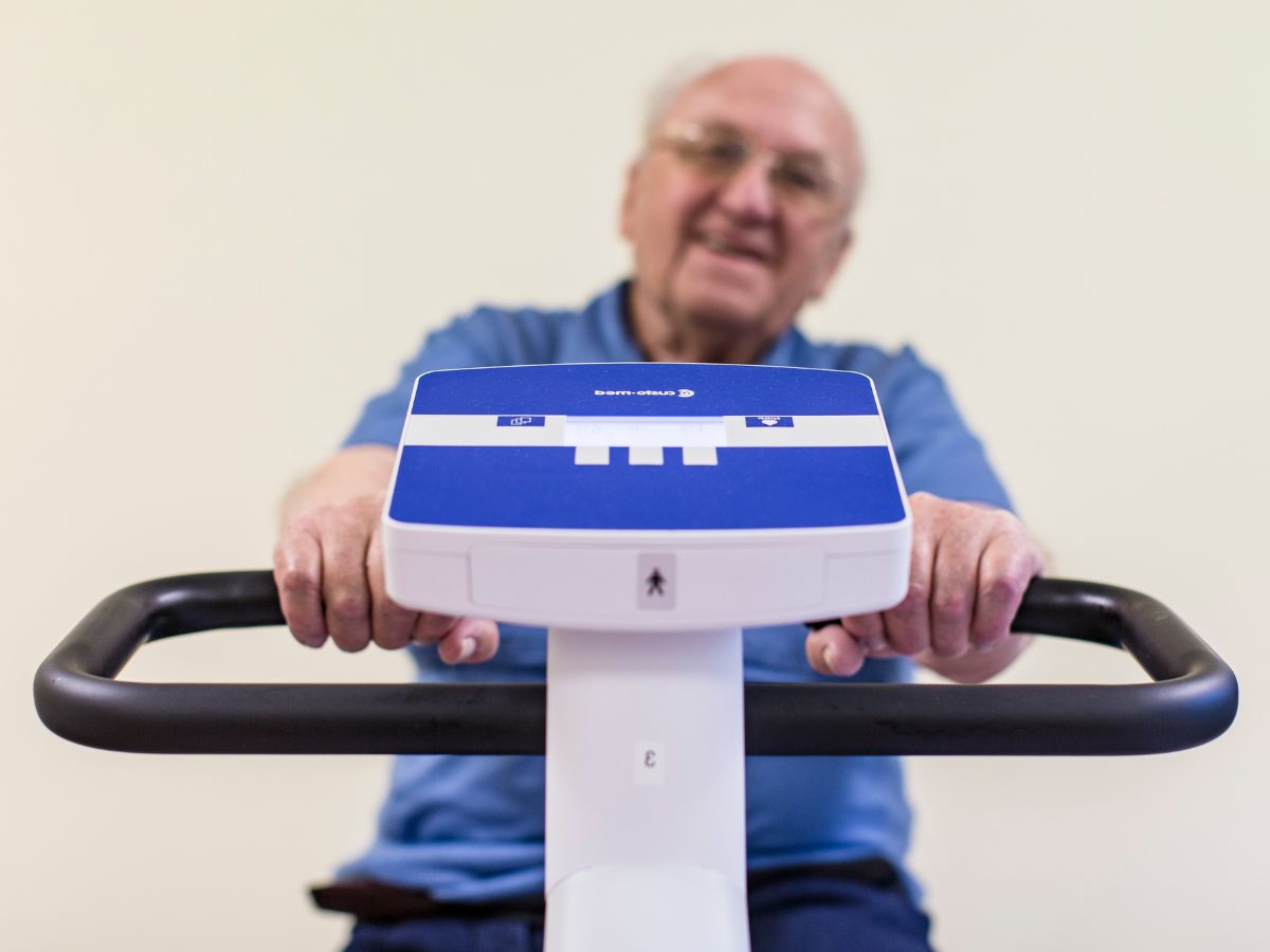 Mann mit Brille sitzt auf dem Ergometer.