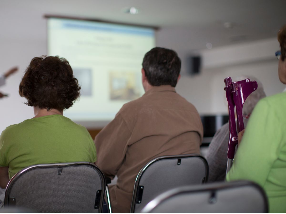 Patienten schauen auf eine Beamer Leinwand im Seminarraum 