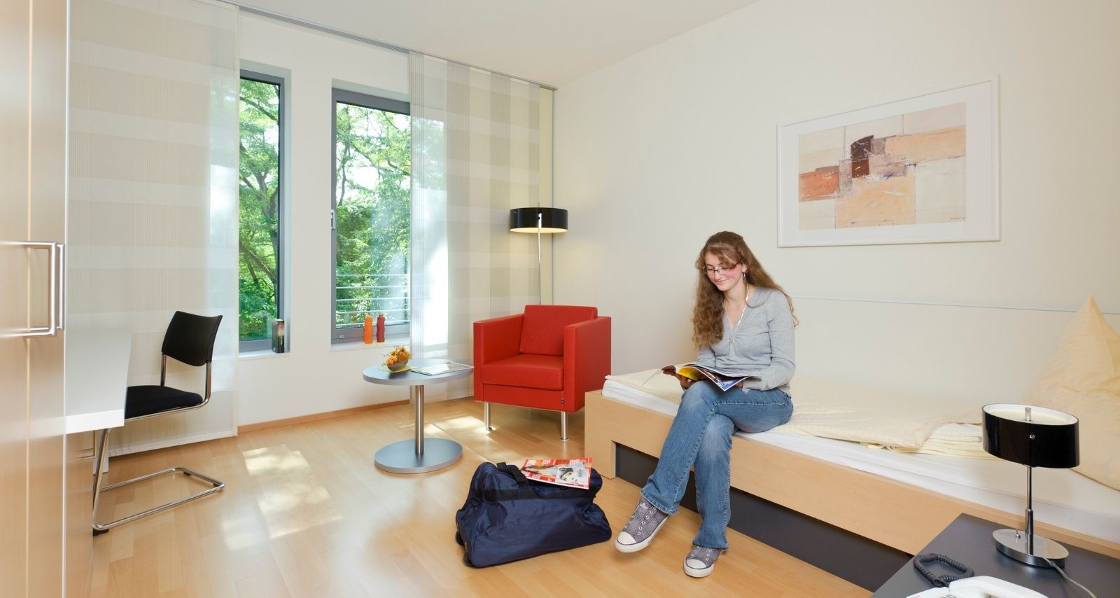 Eine Frau sitzt auf dem Bett und liest eine Zeitschrift 